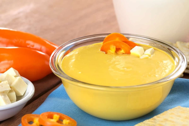 Salsa cremosa color amarillo vibrante en un tazón con papas y ajíes