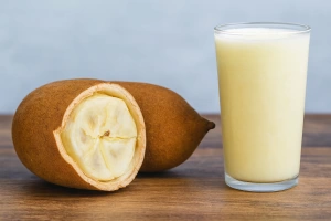 vaso lleno de refresco de copoazú servido bien frío junto al fruto