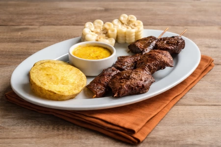 Plato de anticuchos peruanos con choclo y papa dora