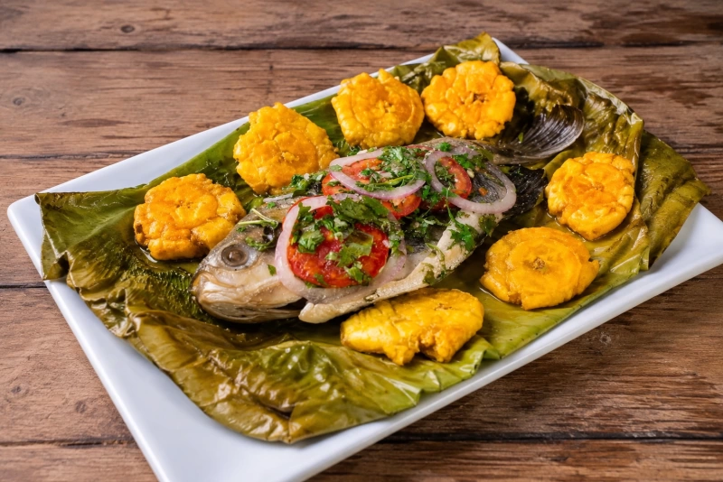 Pescado sobre hojas verdes asado y acompañado de plátano