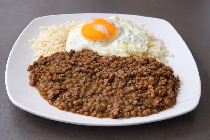 Lentejas cocidas en plato con vegetales y especias coloridas alrededor