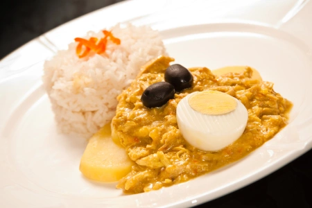 Delicioso ají de gallina servido con arroz blanco papas, huevo y aceituna