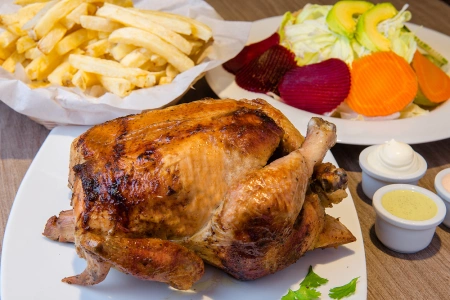 Pollo a la brasa con abundantes papas fritas, ensalada y cremas